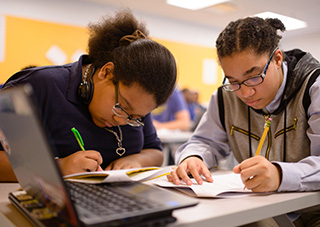wo high-school students work together on an assignment.